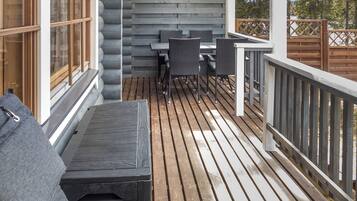 Una terraza de madera con una mesa, sillas, un banco y una barandilla.