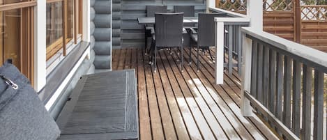 Un ponteggio in legno con tavolo e sedie, una panca e una ringhiera.