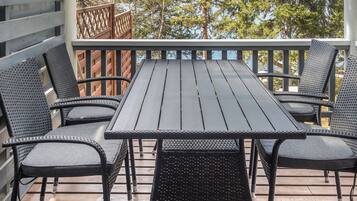 An outdoor patio with a table and chairs, overlooking a body of water and trees.