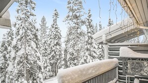 A snow-covered balcony with a railing, overlooking a forest of snow-laden trees. - Vacation home Aino by Interhome (Kuusamo)