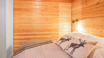 Un dormitorio con paredes de paneles de madera, una cama con colcha acolchada y dos almohadas con motivos de ciervo.