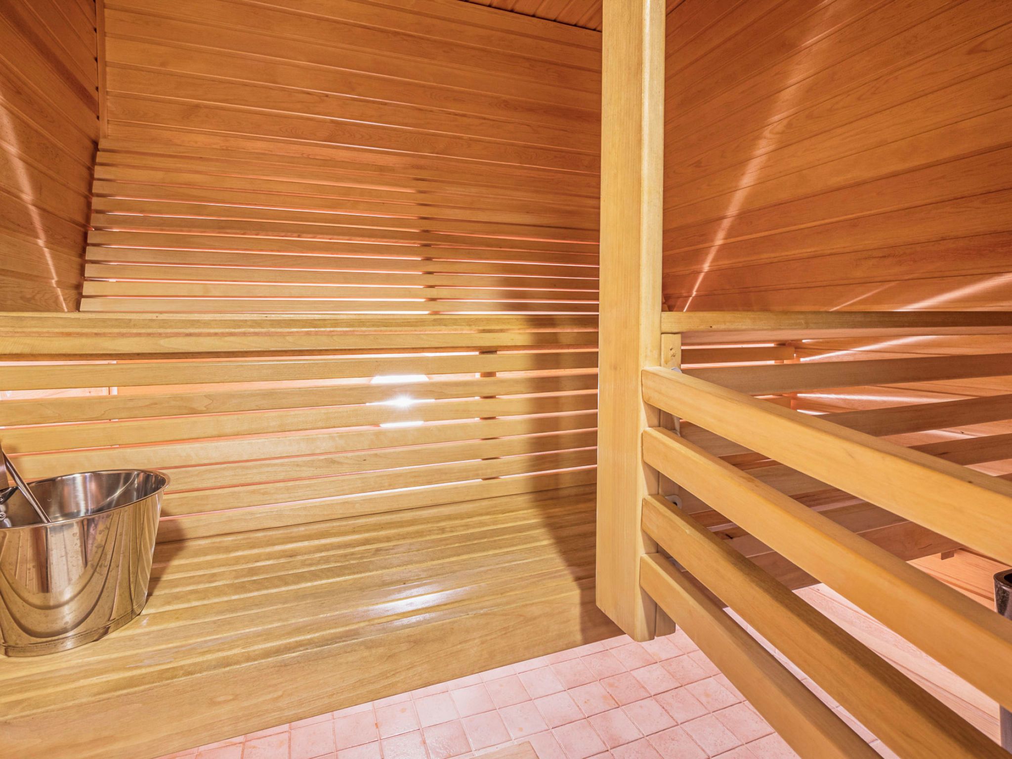 Sauna, jossa on puulankut ja metallinen ämpäri.