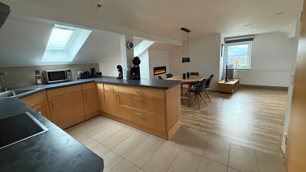 A modern kitchen with a central island, skylights, and a dining area with a view.