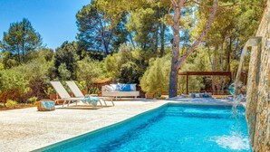Una piscina con sillones de descanso y una cascada.