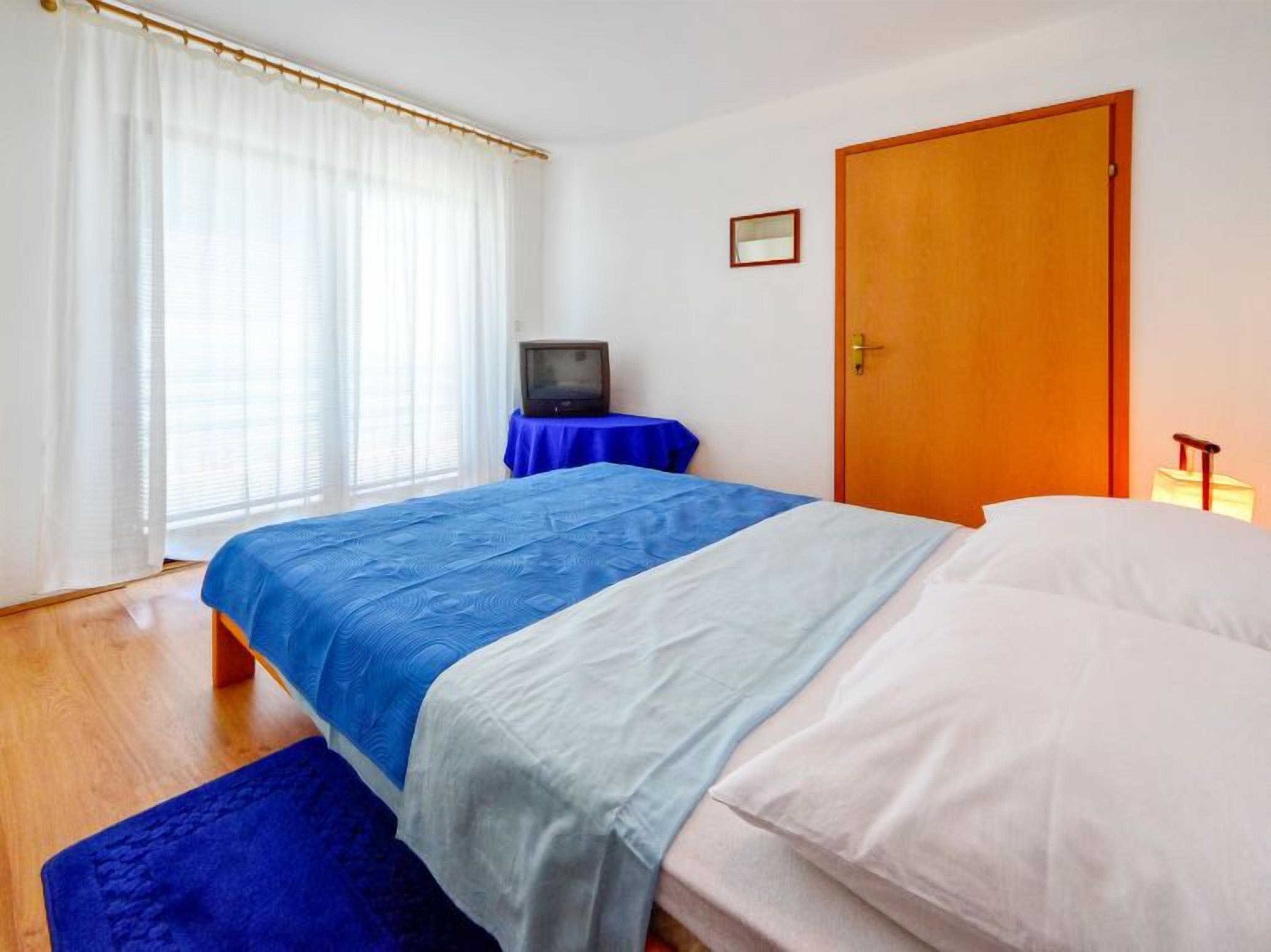 A bedroom with a bed, a television on a table, and a door.