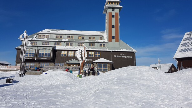 A hotel with a prominent tower and multiple windows, surrounded by snow.