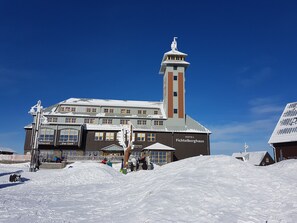 A hotel with a prominent tower and multiple windows, surrounded by snow.