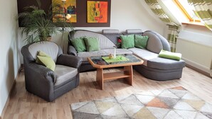 A modern living room with a grey sofa, armchairs, a coffee table, and a large painting on the wall.