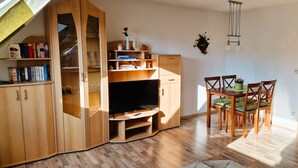 A compact living space with a built-in TV, wooden furniture, and a dining area.