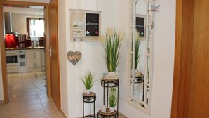 A hallway with a wooden door, a mirror, a wall-mounted chalkboard with handwritten notes, and potted plants. - Vacation apartment in dream location, 92m², terrace, garden, top equipment (Halver)