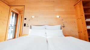 A wooden cabin bedroom with a bed, two bedside lamps, and a window.