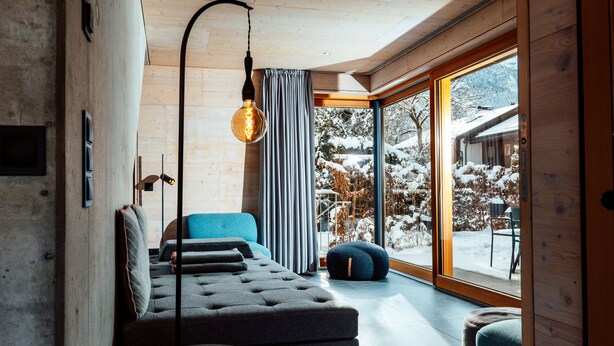 A modern living room with a sofa, a round table, and a large window offering a view of a snowy landscape.