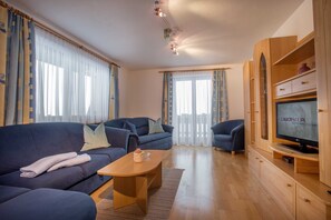 Una sala de estar con un sofá, una mesa de centro y un televisor sobre un mueble de madera.