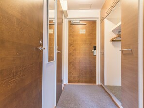 A hallway with wooden doors, a carpeted floor, and a door with a grid pattern.
