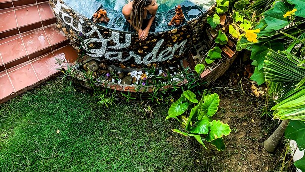 A woman in a garden with a decorative hot tub surrounded by plants and a tiled area. - Fairy Garden Villa (Da Nang)