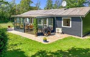 A small house with a glass-enclosed patio, a barbecue, and a satellite dish.