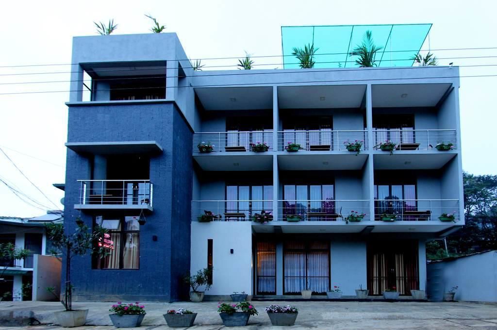 A multi-story building with balconies, potted plants, and a flat roof.