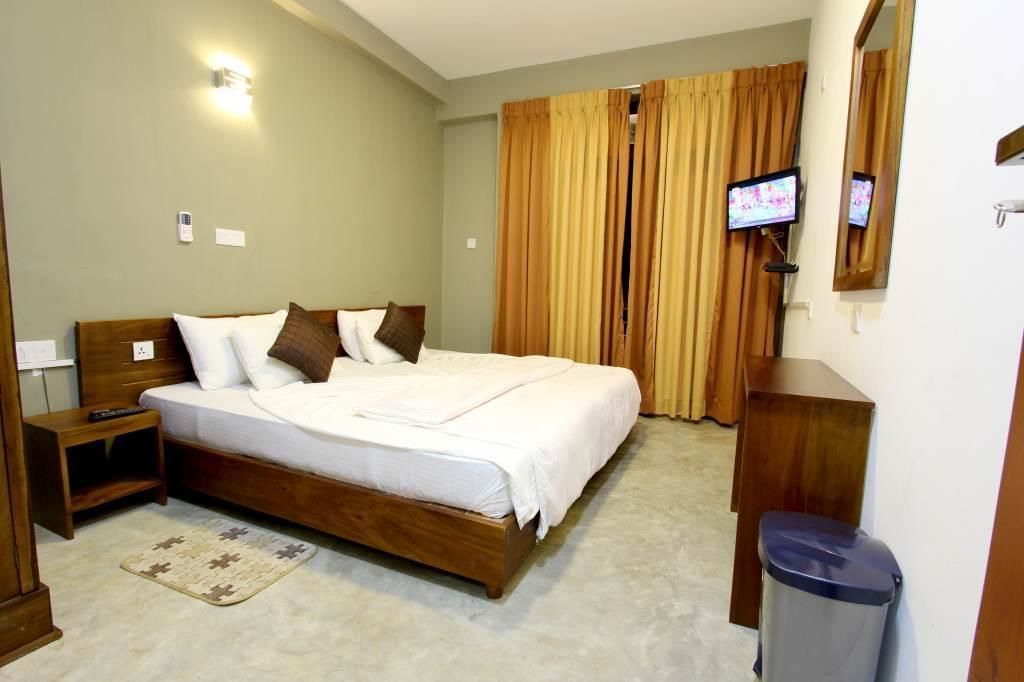 A bedroom with a wooden bed, a nightstand, a TV, and a trash bin.