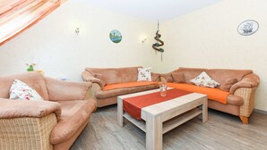 Ein gemütliches Wohnzimmer mit zwei braunen Sofas, einem Holztisch und einem kleinen Beistelltisch mit einer Vase.
