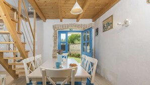 A dining area with a table and chairs, a wooden staircase, and a view of the outside.