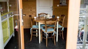 Een houten interieur met een eettafel voor vier personen, omringd door stoelen met geruit kussens.
