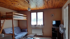 A cozy room with a bunk bed, a small table, a radiator, a television, and a fan. - Holiday rental in Gard near Anduze (Boisset-et-Gaujac)