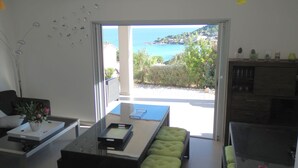Una sala de estar moderna con puerta de vidrio que da a un balcón con vistas al mar.