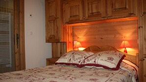 Un dormitorio con cabecera de madera, dos lámparas de noche y una colcha estampada.