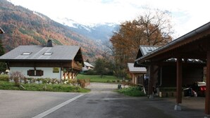 Un albergue de montaña con zona de estacionamiento techada y un edificio pequeño con tejado inclinado.