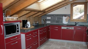 Una cocina compacta con armarios rojos, un microondas, una cafetera y una ventana sobre el fregadero.