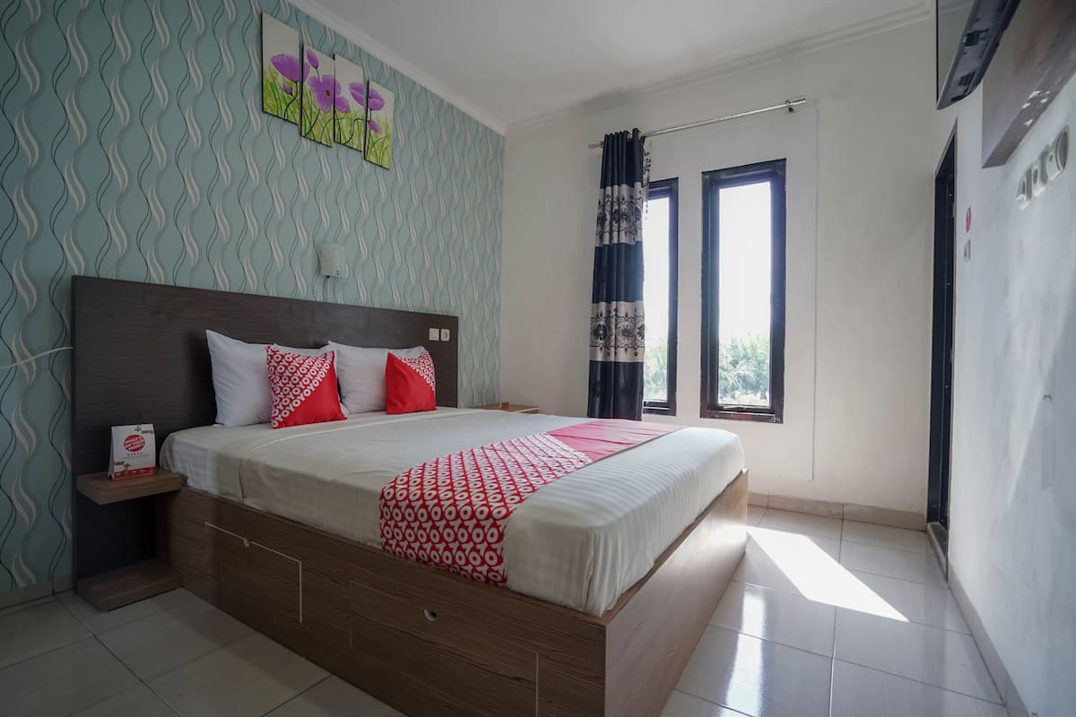 A bedroom with a bed, a nightstand, a window, and a wall with a wavy pattern.