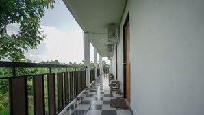 A corridor with a checkered floor, a railing, and a view of greenery. - Hotel O Green Palm Kostel Syariah (Lubuklinggau)