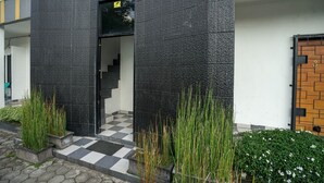 A modern building with a black exterior, a checkered entrance, and a wooden door. - Hotel O Green Palm Kostel Syariah (Lubuklinggau)