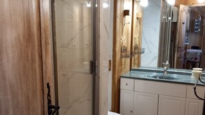 A bathroom with a glass shower door, a sink with a marble countertop, and wooden paneling. - The charm of an alpine chalet, an ideal location for sport and shopping (Mont-de-Lans)