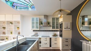 A modern kitchen with white cabinetry, a central island with a sink, and a large mirror on the wall.