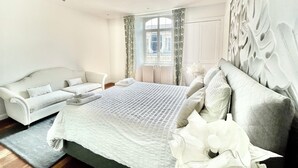 A modern bedroom with a large bed, a sofa, and a decorative wall.