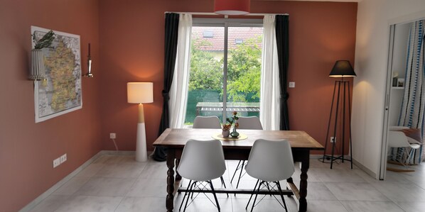 Enjoy meals in this cozy dining area with a wooden table and four chairs, accompanied by a map on the wall and a floor lamp.