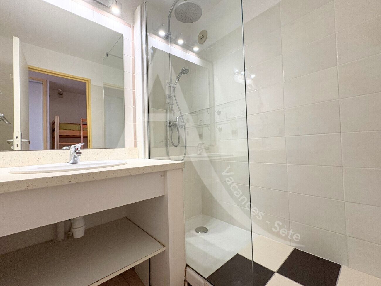 A modern bathroom with a glass shower enclosure, a white sink, and a large mirror.