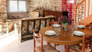 Un coin repas avec une table ronde en bois, dressée pour quatre personnes, entourée de chaises en osier.