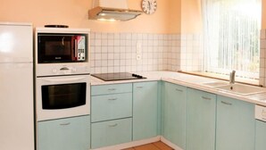 Une cuisine avec des appareils électroménagers blancs, des meubles de couleur bleu clair et un sol carrelé.