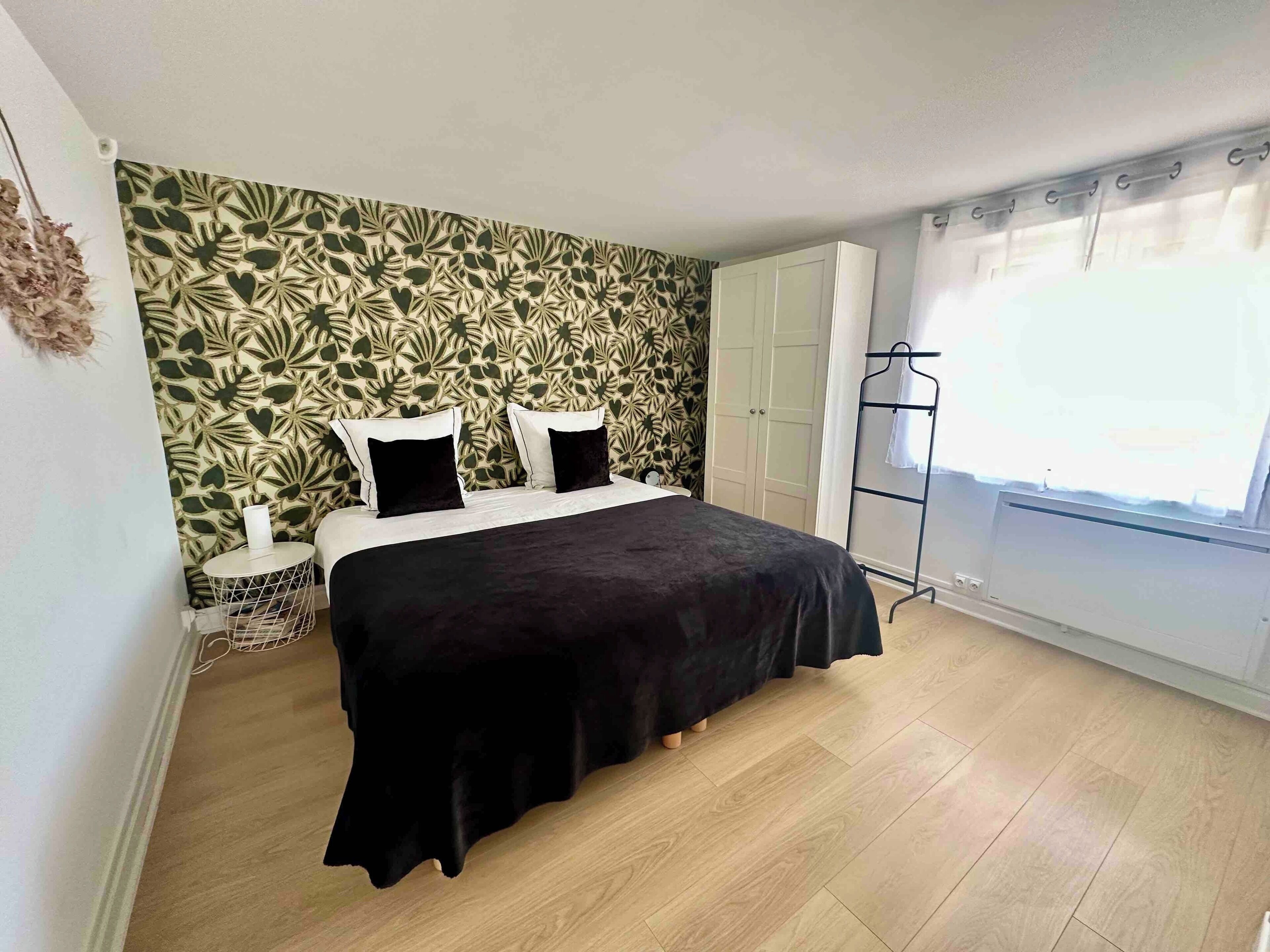 Ein Schlafzimmer mit einem Bett, einem Kleiderschrank, einem Heizkörper und einem Fenster mit Vorhängen.