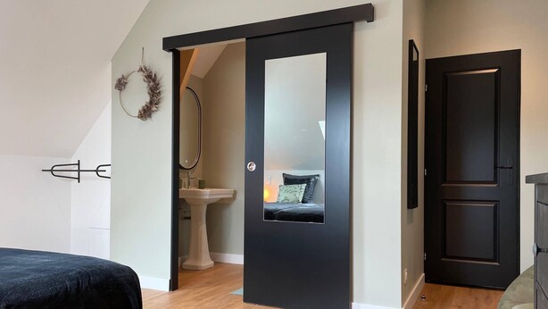 A bedroom with a bed, a black sliding door, a white sink, and a mirror. - MAGNIFICENT VIEW HOUSE PARADISIAC IN THE MIDDLE OF VINES OF BOURGOGNE (Rully)