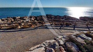 En stenig kustlinje med ett trästaket och fri utsikt över havet.