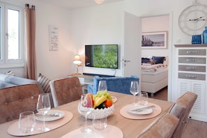 Una habitación de hotel moderna con zona de comedor, televisión y cama.
