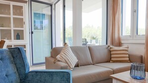 Ein modernes Wohnzimmer mit Sofa, Sessel und einer Glasvitrine.