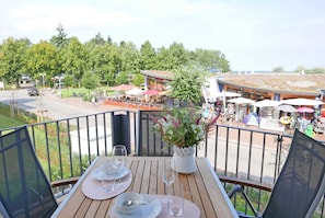 Varanda com mesa posta para dois, vista para um parque e um edifício com área externa.