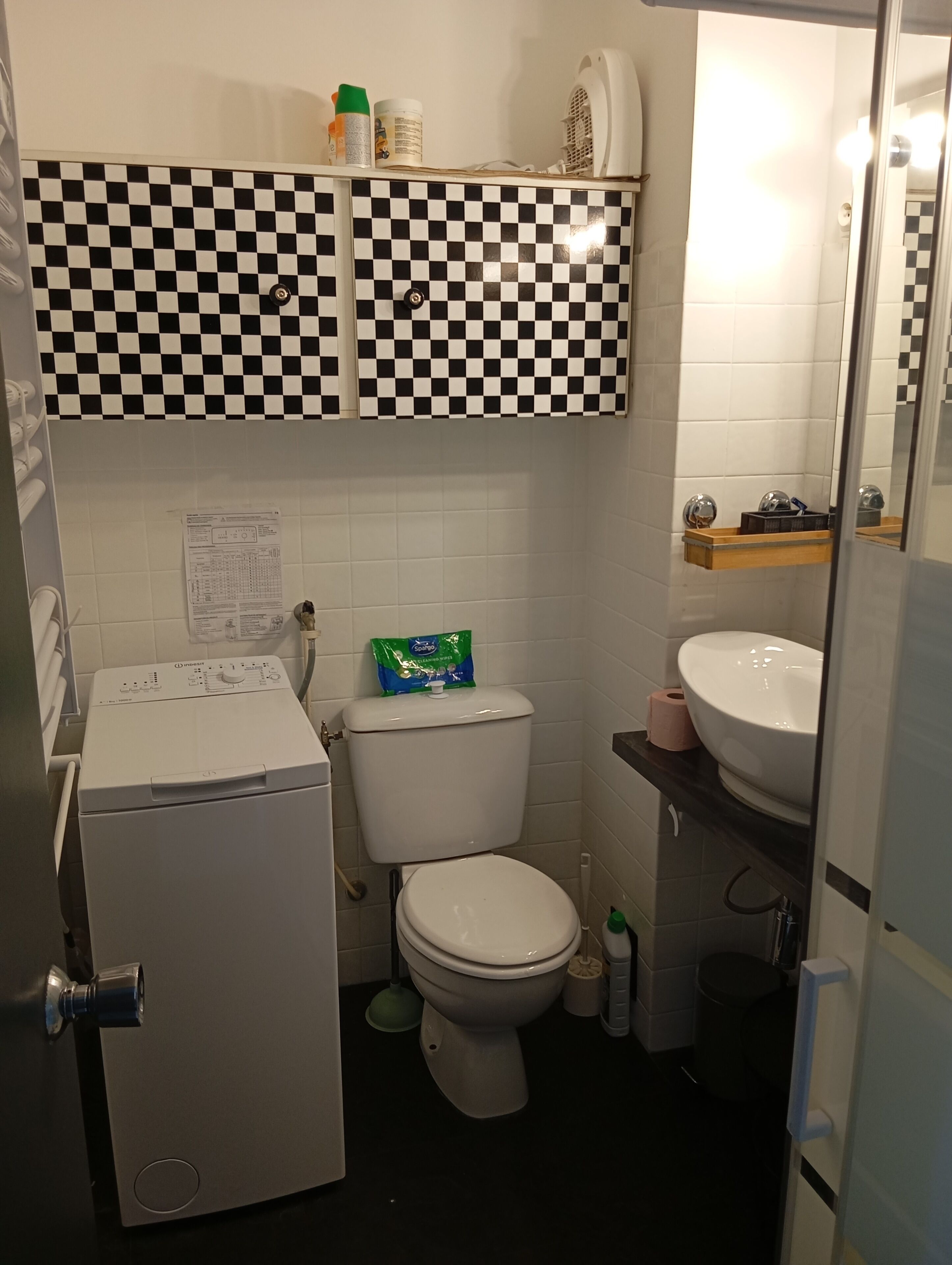 Ett litet badrum med toalett, handfat och en kompakt tvättmaskin.