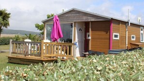 Une cabane en bois dotée d’un balcon et d’une véranda couverte.
