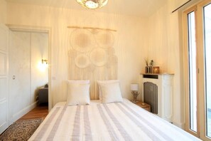 Une chambre à coucher avec un grand lit, une décoration murale, une petite table avec une lampe et une fenêtre donnant sur un beau paysage.
