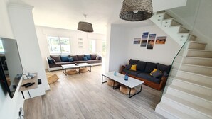 Een ruime woonkamer met een modern design, voorzien van een bank, salontafel en een trap.